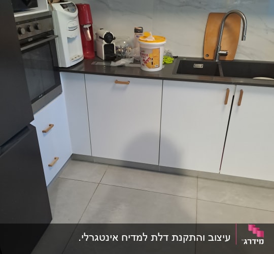מטבח עם כיור, ארונות ומכשירי חשמל קטנים על השיש